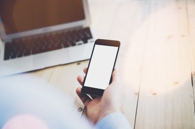 Working process. Businessman working at the wood table with new project . Contemporary notebook on table. Modern smartphone holding hand. Horizontal mockup. Flares, film effect