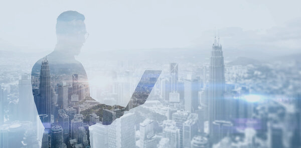Double exposure photo bearded businessman wearing black shirt and glasses.Banker holding contemporary notebook hands,work online banking.Panoramic view modern skyscraper city background.Soft light