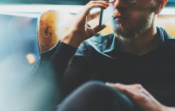 Foto skäggiga affärsman avkopplande moderna loft office. Bankman sitter i vintage stol, talande mobiltelefon. Med hjälp av modern smartphone. Suddig bakgrund. Verkan i hela, film. — Stockfoto