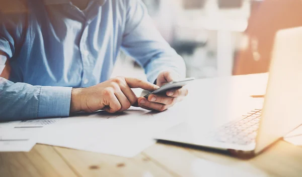 Kontorliv. Forretningsmann på trebordet med nytt forretningsprosjekt. Mann som tar på skjermen moderne mobiltelefon. Horisontal modell. Signalbluss, filmeffekt – stockfoto