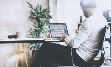 Resim sakallı hipster yeni proje modern loft ile çalışıyor. Ahşap masa üzerinde tefeksyon dizüstü bilgisayar kullanma. Yaratıcı süreç. Serbest dünya. Bulanık arka plan, film efekti, yatay