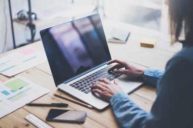 Working process photo.Woman working wood table with new business project.Typing contemporary laptop, reflections screen.Modern smartphone and documents table.Horizontal.Film effect. Blurred background