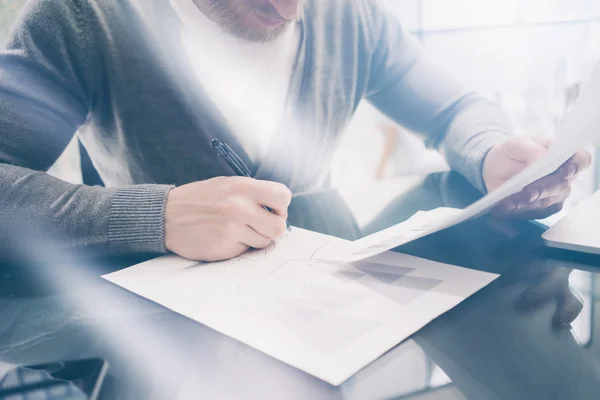 Working process. Bearded account manager working at the wood table with new business project.Holding pen hand, signs document and analyze plans. Horizontal mockup, sunny effect. Blurred, film effect — Zdjęcie stockowe