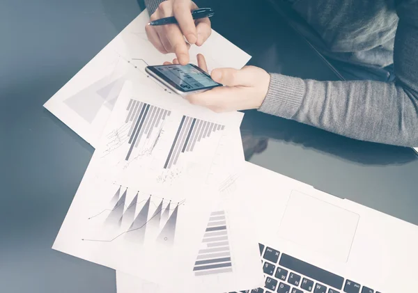 Foto-Account-Manager arbeitet am Tisch mit neuen Geschäftsprojekten. moderne Smartphone-Hand, Touchscreen-Statistiken. Schilder dokumentieren und analysieren Pläne. horizontal, unscharf, Filmeffekt — Stockfoto