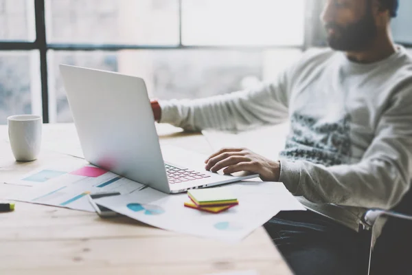 Picture bearded graphic designer working with new project modern loft. Using contemprary laptop on wood table. Creative process. Freelance world. Blurred background, film effect, horizontal — Stock Photo, Image