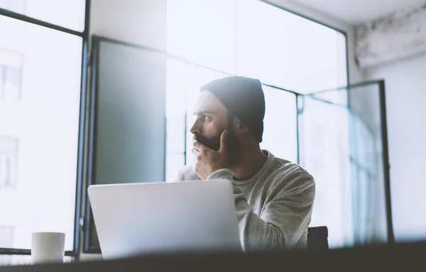 Photo bearded graphic designer working with new project modern loft. Using contemprary notebook on wood table. Thinking idea. Freelance world. Blurred background, film effect — Stock Photo, Image