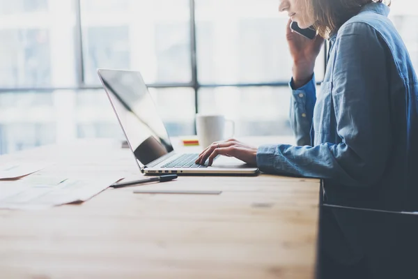 Processo di lavoro ufficio moderno. Account manager che lavora tavolo in legno con nuova start-up aziendale. Digitando laptop contemporaneo, tenendo per mano smartphone, riflessioni.Orizzontale.Effetto pellicola. Sfondo sfocato — Foto Stock