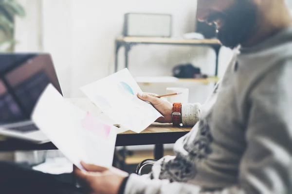 Foto bebaarde account manager werken met documenten moderne kantoor. Overweegt notitieboekje op houten tafel. Bedrijfsplannen analyseren. Coworking wereld. Onscherpe achtergrond, filmeffect — Stockfoto