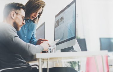 Coworking süreci, modern ofis çalışan tasarımcılar ekibi. Fotoğraf genç yaratıcı yöneticisi yeni başlangıç proje tablet gösteren. Ahşap masa üzerinde masaüstü bilgisayarlar. Bulanık arka plan, film efekti. Yatay