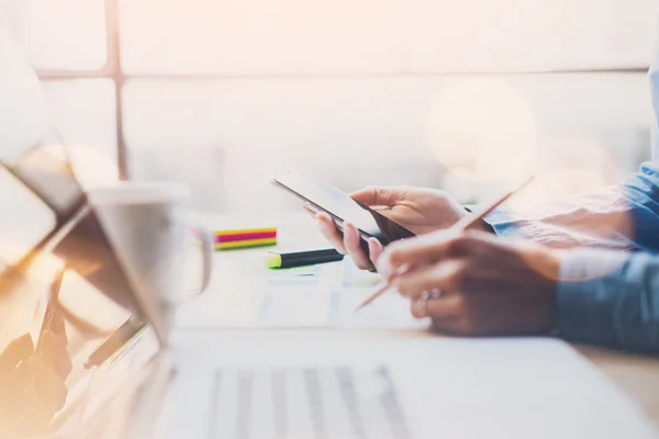 Processo di lavoro ufficio moderno. Finance manager tavolo di lavoro in legno con nuove startup.Contemporary smartphone mani, in possesso di matita. Orizzontale. Effetti di film e bagliori. Sfondo sfocato — Foto Stock