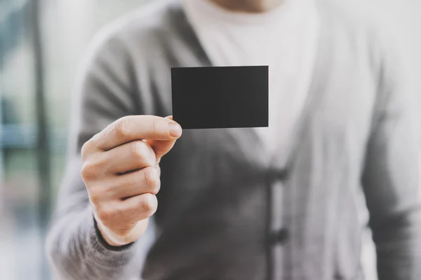 Man draagt casual shirt en toont lege zwarte visitekaartje. Onscherpe achtergrond. Horizontale mockup — Stockfoto