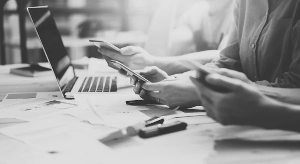 Le coworking d'équipe. Photo jeune équipe d'affaires travaillant avec un nouveau projet de démarrage.Carnet sur table en bois. En utilisant des smartphones modernes, en tapant un message, analyser les plans. Fond flou, effet filmoire.Large — Photo