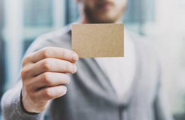 Casual gömlek giymiş ve boş el sanatları iş kartı gösteren dostum. Arka plan bulanık. Özel bilgi için hazır. Yatay mockup