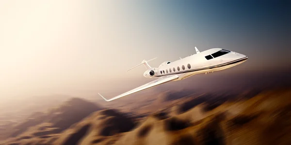 Image of white modern and luxury generic design private jet flying in blue sky over uninhabited desert.Mountains background.Business travel concept. Horizontal,motion blurred effect. 3d rendering — Stock Photo, Image