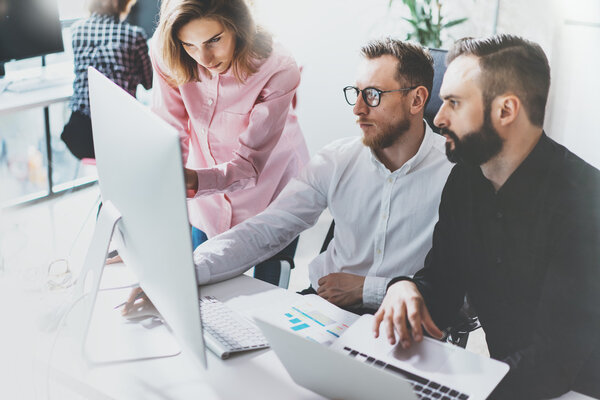 Команда менеджеров проекта работает над новой идеей. Молодая бизнес-команда работает со стартапом современной студией.Настольный компьютер на столе, демонстрирует презентацию.
