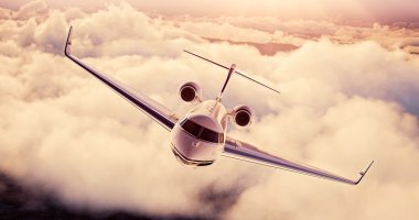 Gün batımında dünya üzerinde uçan Beyaz Lüks jenerik tasarım özel uçak Gerçekçi görüntü. Büyük beyaz bulutlar arka plan ile boş mavi gökyüzü. İş Seyahati Konsepti. Yatay. 3d render