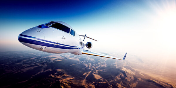 Realistic image of White generic design private jet flying over the mountains.Empty blue sky and sun at background.Business Travel by modern Luxury aircraft.Horizontal,side view closeup. 3d rendering