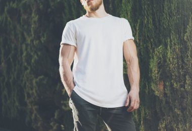 Görüntü Sakallı Kaslı Adam Beyaz Boş t-shirt giyiyor. Gün batımında Green City Garden Arka Plan. Yatay Mockup
