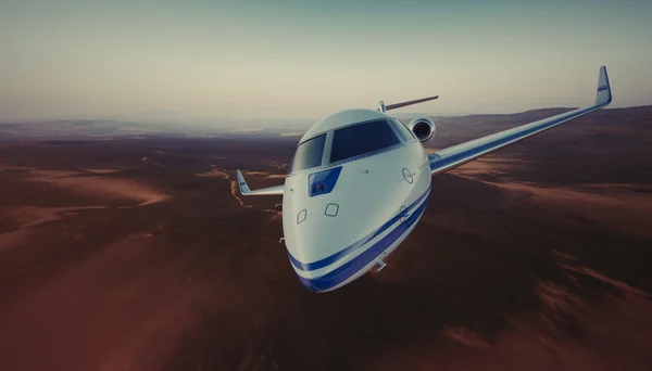 照片的白色豪华通用设计私人喷气式飞机在天空下地球表面飞行。无人居住的沙漠山脉背景。商务旅行图片。宽，前视图。电影效果。3d 渲染. — 图库照片