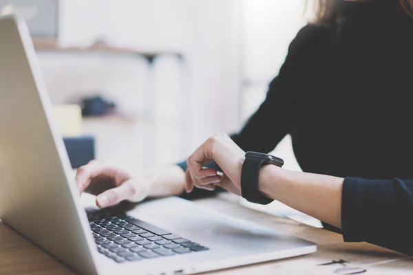 Foto meisje werken moderne laptop in Studio loft. Vrouw kijken naar scherm generieke design SmartWatch. Manager werkproces. notitieboekje op de houten tafel. horizontale, rode achtergrond. Film effecten — Stockfoto