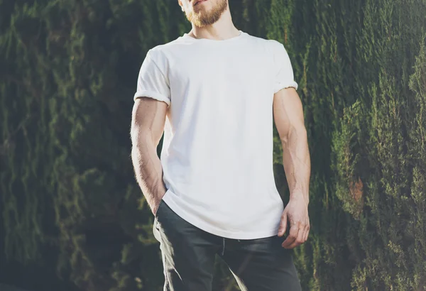 Image Bearded Muscular Man Wearing White Blank t-shirt. Green City Garden Background at sunset. Horizontal Mockup — Stock Photo, Image