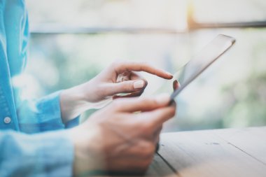 Modern Stüdyo 'nun çalışma süreci. Hippi, yeni serbest iş girişimiyle ahşap masa üzerinde çalışıyor. Dijital Tablet, Dokunmatik Ekran kullanılıyor. Yatay. Film efekti, işaret fişeği. Arka plan bulanık. Yakın plan fotoğraf.