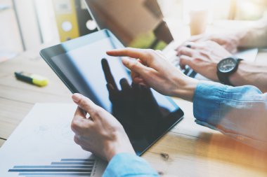 Work Process in Modern Office. Young Account Manager Working at Wood Table with New Business Project.Touching Screen Digital Tablet.Man using Laptop.Horizontal. Film effect. Blurred backgrou