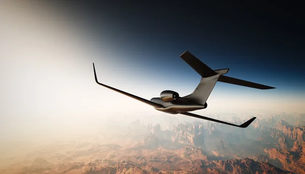 Foto de Black Matte Luxury Generic Design Private Jet Volando en el cielo bajo la superficie de la Tierra. Fondo del Gran Cañón. Viajes de negocios. Horizontal, vista angular hacia atrás. Efecto de película. Renderizado 3D . — Foto de Stock