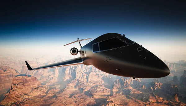 Primo piano Black Matte Luxury Generic Design Private Jet Volare in cielo sotto la superficie terrestre. Sfondo del Grand Canyon. Foto di viaggio d'affari. Vista orizzontale, angolare. Effetto pellicola. Rendering 3D . — Foto Stock