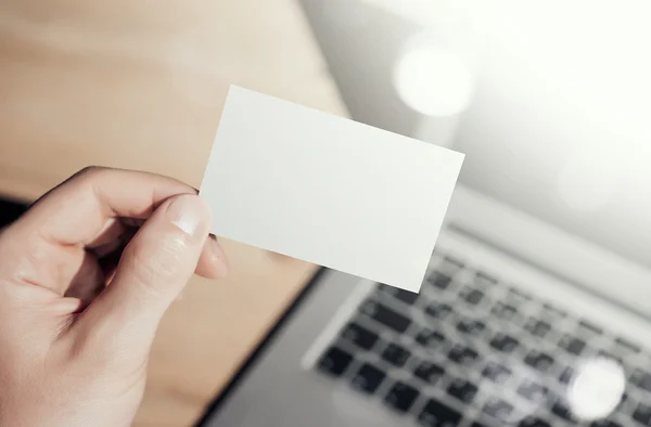 Closeup Photo Man Showing Blank White Business Card and Using  Modern Laptop.Wood table Blurred Background. Mockup Ready for Private Information.Sunlight Reflections Screen Gadget. Horizontal mock up. — Stock Photo, Image