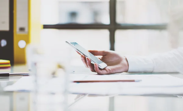 Mujer de negocios de fotos con camisa blanca, sosteniendo las manos de teléfonos inteligentes. Moderna oficina de loft. Fondo borroso. Imagen horizontal. Efecto película —  Fotos de Stock