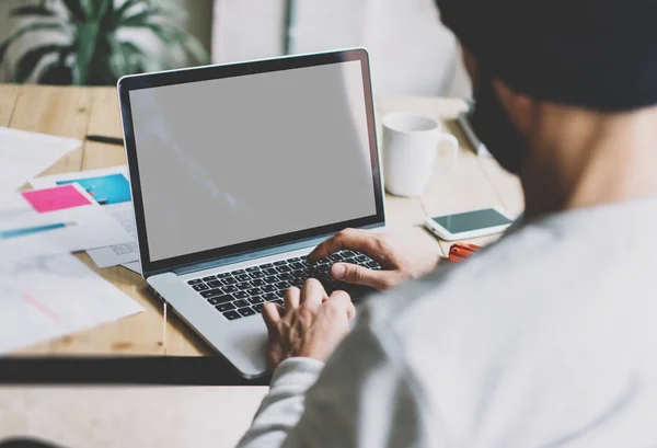 Photo bearded graphic designer working with new project modern loft.Using contemprary laptop wood table.Creative process.Mock up notebook reflections screen.Blurred background, film effect, horizontal — стоковое фото