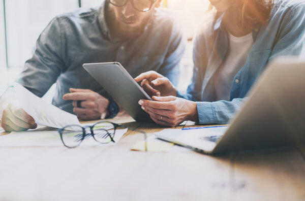 Коворкинг. Фотография молодых бизнесменов, работающих с новыми проектами стартапов. Женщина показывает экран цифровой планшет, мужчина держит report.Blurred фона, фильм Efft.Horizontal
