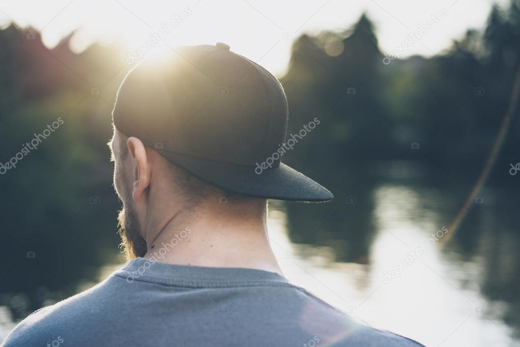 照片胡子的年轻人穿着黑色空白帽 绿城公园湖背景和日落效果 后视图 水平模拟 图库照片 C Kantver 照片胡子的年轻人穿着黑色空白帽 绿城公园湖背景和日落效果 后视图 水平模拟 图库照片 C Kantver