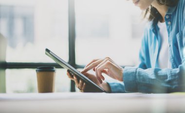 Modern Stüdyo Çalışma Süreci. Genç kız hippi yeni serbest iş girişimiyle ahşap masa üzerinde çalışıyor. Dijital Tablet, Dokunmatik Ekran kullanılıyor. Yatay fotoğraf. Film efekti. Bulanık arkaplan.