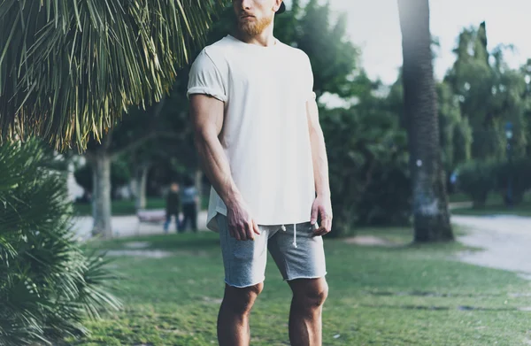 图片胡子肌肉男子穿着白色空白T恤在夏季时间。绿城花园.辛苦工作一天后的放松时间。模糊背景.前视图。水平模拟. — 图库照片