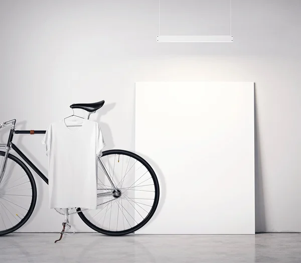 사진 인테리어 현대 스튜디오 로프트 콘크리트 벽과 클래식 자전거. 바닥에 빈 흰색 캔버스, 스포트라이트 상단. 빈 티셔츠 매달려 자전거입니다. 스퀘어 모형. — 스톡 사진