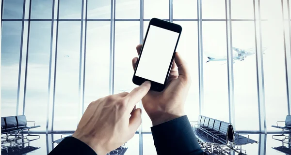 Fotó üzletember gazdaság modern okostelefon Hand megnyomja a gombot. Üres képernyő elszigetelt fehér, repülőgép felszállás, a repülőtéri háttérben. Készen áll a személyes adatok. Üzleti utazás mockup. Széles. — Stock Fotó