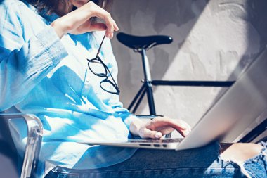 Çalışma süreci Modern Stüdyo Loft. Yaratıcı Yönetici, yeni bağımsız iş koluyla çalışıyor. Dizüstü bilgisayar, gözlük, el. Yatay. Film efekti..