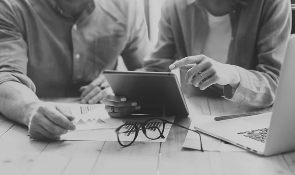 Coworkers team brainstorming process modern loft.Project producer reading report tablet, glasses wood table.Young business crew working startup studio.Using Laptop.Blurred, film effec. Черный белый — стоковое фото