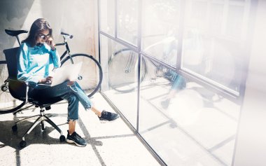 Hipster Kız Laptop modern ve güneşli Loft Studio.Student Araştırma Süreci Work Time.Young Business Woman Creative Startup.Panoramic pencere arka plan kullanarak. Bulanık, film efekti. Yatay.