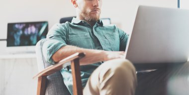 Sakallı İşadamı çalışma Laptop modern İç Tasarım Loft Studio.Man rahatlatıcı Vintage sandalye. Çağdaş Not Defteri, bulanık arka plan kullanın. Yaratıcı Süreç Yeni Başlangıç Fikirler.Wide, film effec