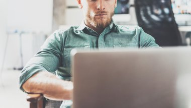 Sakallı Stil İşadamı iş Laptop modern Tasarım Interior Loft Studio Place.Man ürpertici Vintage sandalye. Çağdaş Not Defteri, bulanık arka plan kullanın. Yaratıcı Süreç Yeni Başlangıç Idea.Film etkisi.