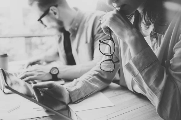 Coworkers team brainstorming process in modern office e.Project manager thinking, holding glasses female hand.Young business crew working wit startup studio.Laptop table, using tablet.Black White.Blurred . — стоковое фото