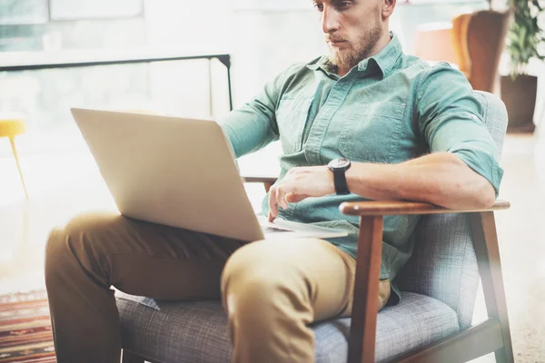 Bearded Businessman working Laptop modern Interior Design Loft Studio.Man relaxing Vintage chair.Use contemporary Notebook, blurred background.Creative Process New Startup Ideas.Horizontal, film effec — стоковое фото