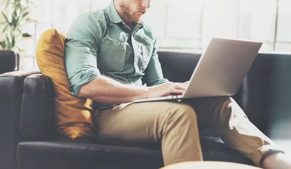 Bearded hipster werken laptop modern interieur Loft Office. man werk klassieke sofa, gebruik hedendaagse notebook, typen toetsenbord. Onscherpe achtergrond. creatief bedrijf startup idee. horizontaal, film effe — Stockfoto