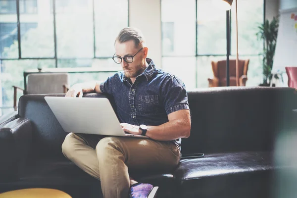 Succesvolle manager werken laptop modern design interieur Loft Studio. man zitten Vintage sofa, gebruik hedendaagse notebook, surfen op wereldnieuws. onscherpe achtergrond. Business Startup idee proces. horizontaal. — Stockfoto