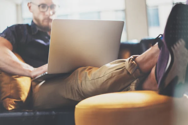 Bearded Hipster working Laptop modern Interior Design Loft Office.Man work Vintage Sofa,Use contemporary Notebook,Browsing Internet.Blurred Background.Creative Business Startup Idea.Horizontal,Film.