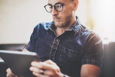 Sakallı yönetici çalışma tablet cihaz modern İç Tasarım Loft Building.Man vintage kanepe kullanımı çağdaş bilgisayar Hand.Blurred arka plan dinlenmek. Yaratıcı iş başlangıç Idea.Closeup, Film effec