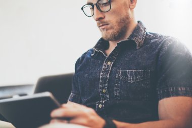 Sakallı tüccar çalışma tablet bilgisayar modern İç Tasarım Loft Building.Man vintage kanepe kullanımı çağdaş cihaz Hand.Blurred arka plan dinlenmek. Yaratıcı iş başlangıç Idea.Closeup, Film effec